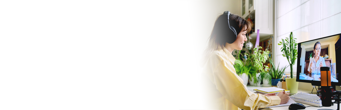 Young woman wearing headphones and taking notes while working with an online tutor